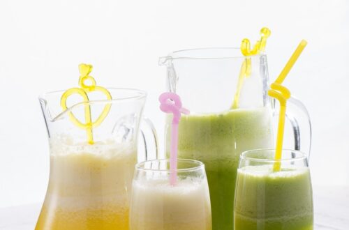 Copos de suco detox coloridos, rodeados por frutas frescas, folhas de hortelã e gengibre, simbolizando saúde, frescor e bem-estar.
