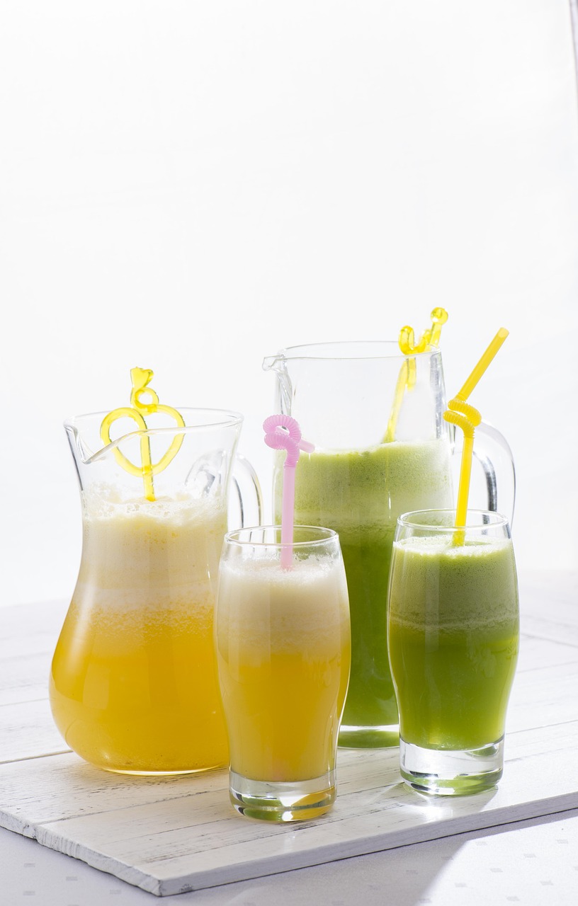 Copos de suco detox coloridos, rodeados por frutas frescas, folhas de hortelã e gengibre, simbolizando saúde, frescor e bem-estar.