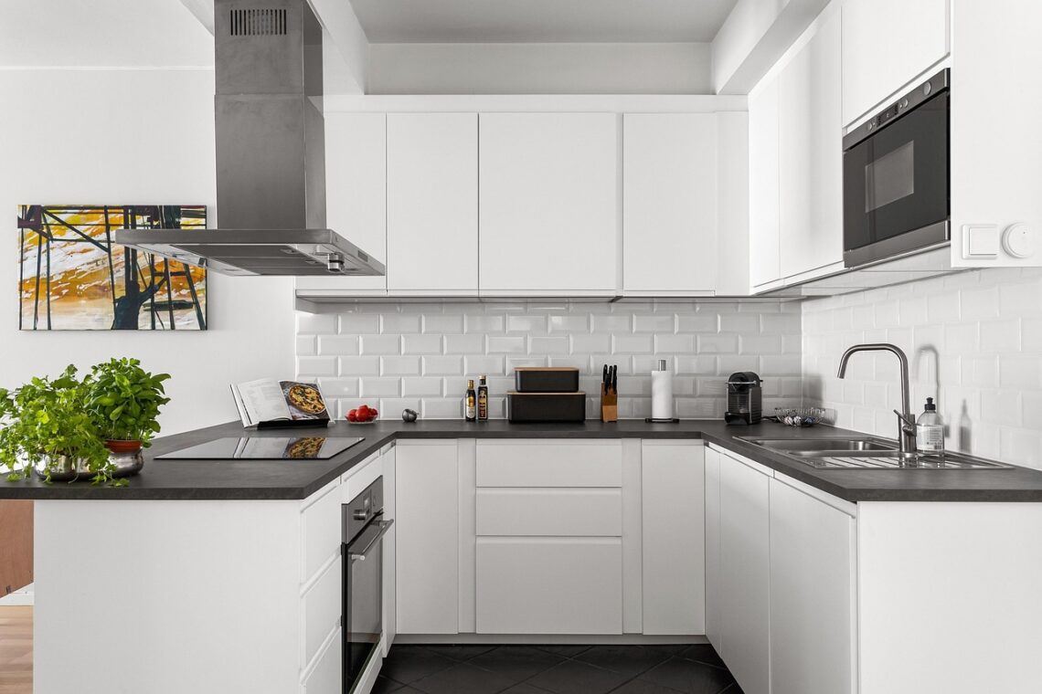 Cozinha organizada com potes de vidro etiquetados, bancadas limpas e utensílios pendurados em organizadores.